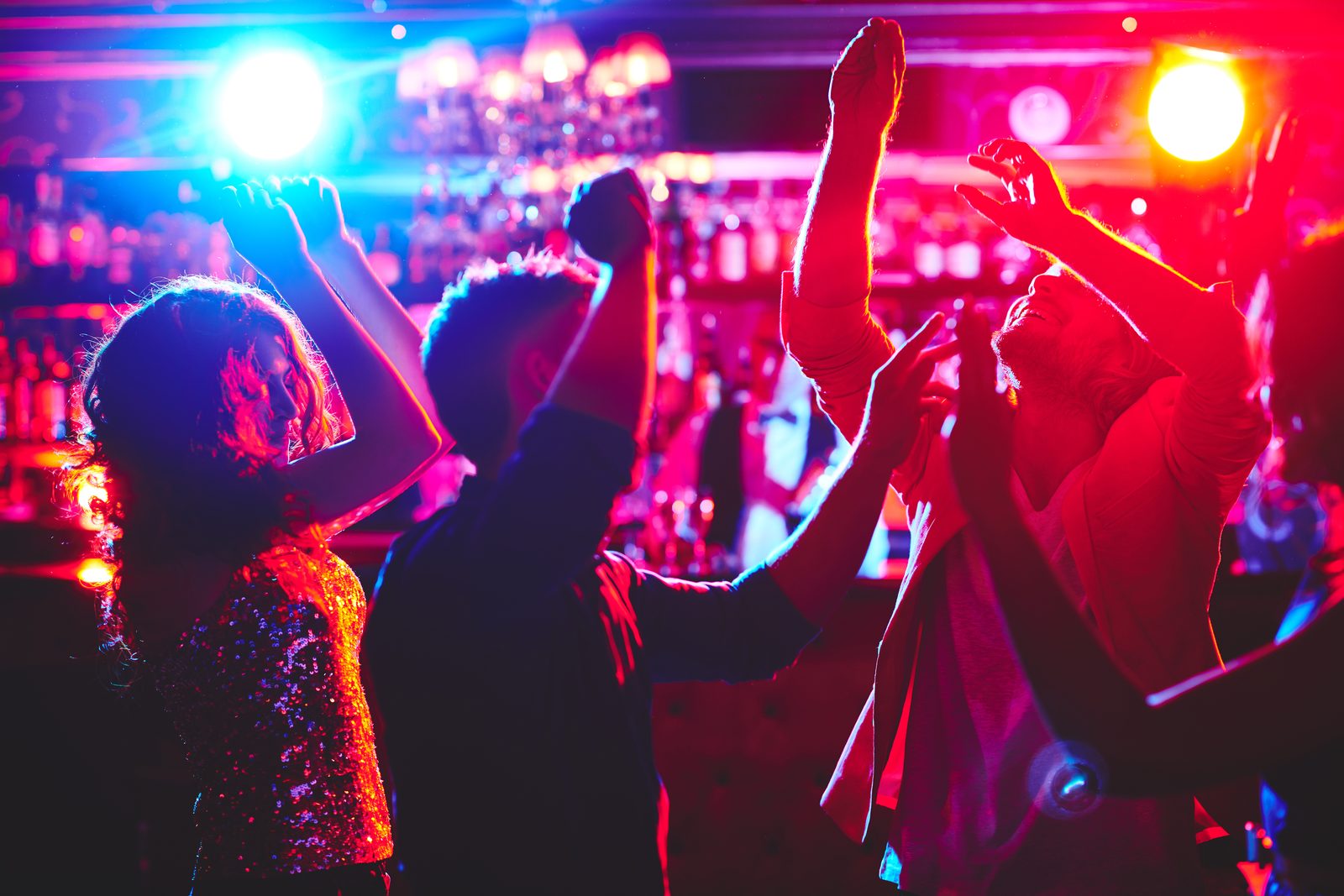 Guests dancing under colorful lights at a lounge bar